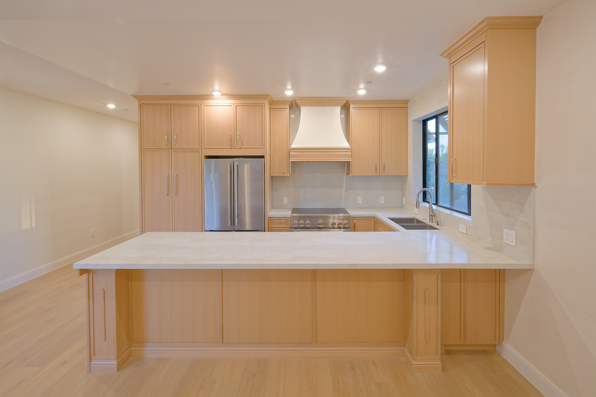 Completed project — 1: Completed kitchen with light wood cabinetry, a stone peninsula, and stainless steel appliances